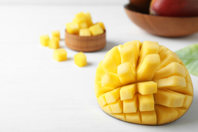 Photo of Cut fresh ripe mango on white wooden table. Space for text