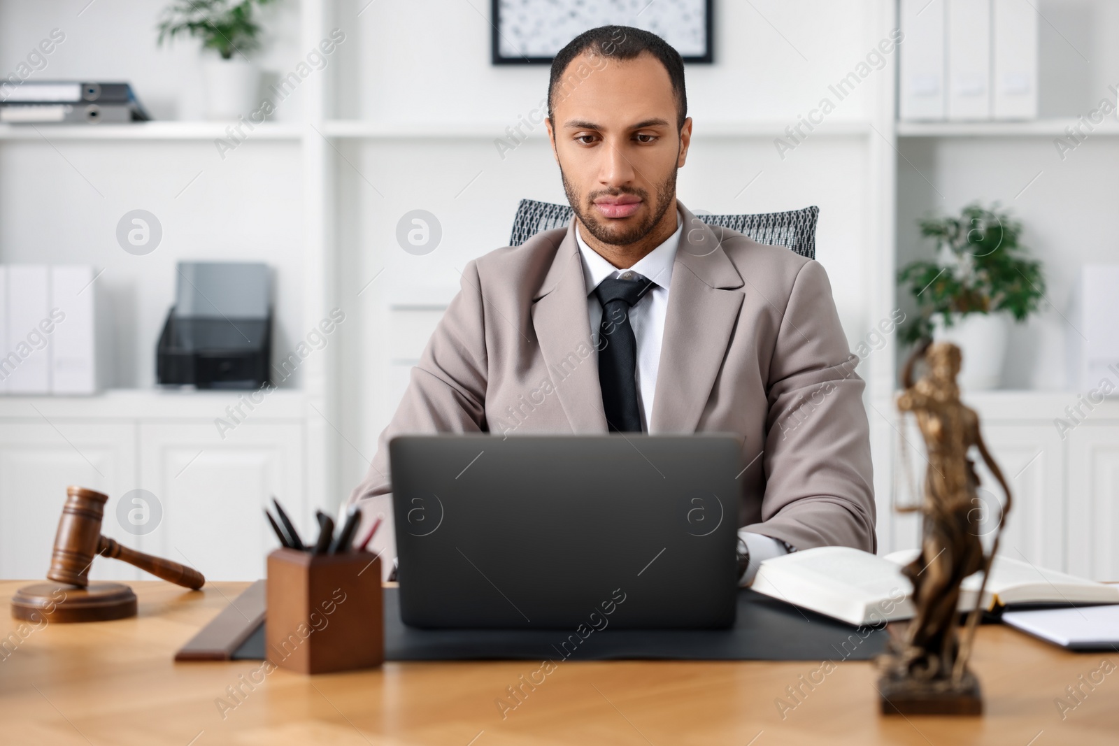 Photo of Serious lawyer working with laptop at table in office