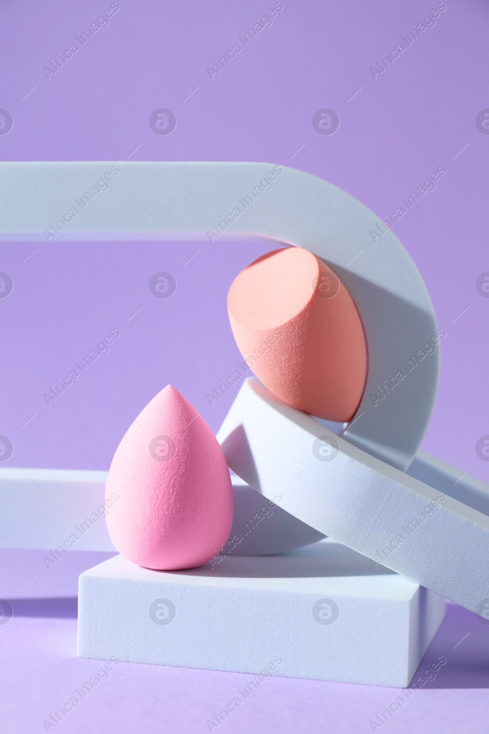 Photo of Stylish presentation of makeup sponges on violet background