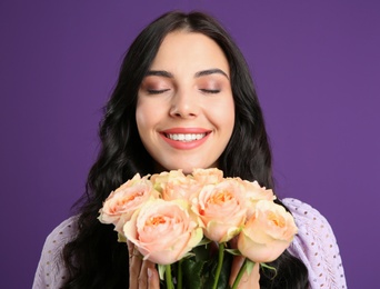 Photo of Portrait of smiling woman with beautiful bouquet on purple background