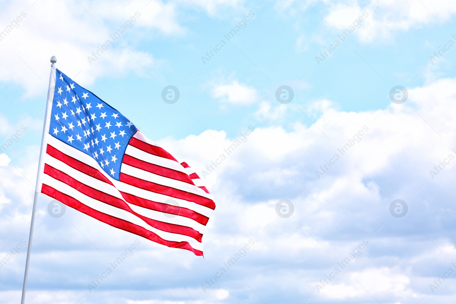 Photo of American flag outdoors on cloudy day. Space for text