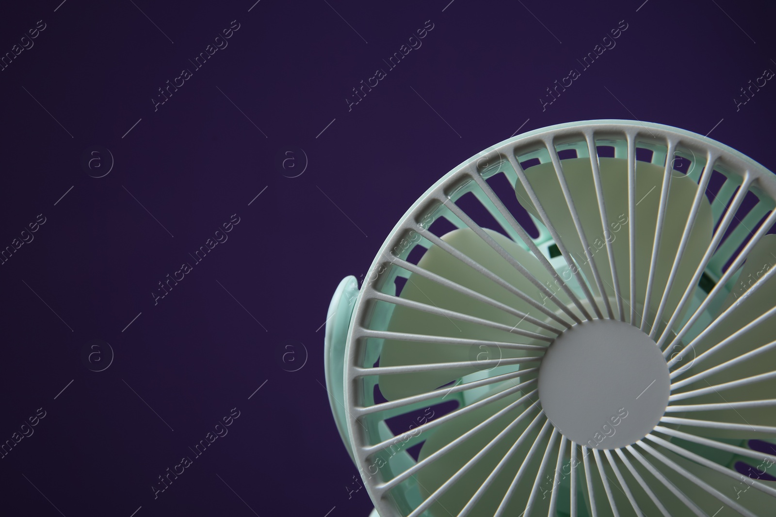 Photo of Modern electric fan on violet background, closeup. Space for text