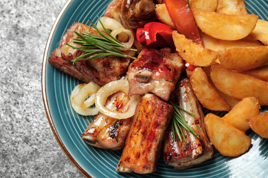 Photo of Delicious grilled ribs and garnish on grey table, closeup
