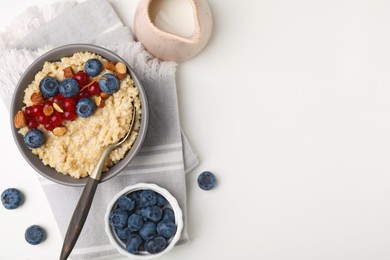 Photo of Bowl of delicious cooked quinoa with almonds, cranberries and blueberries on white background, flat lay. Space for text