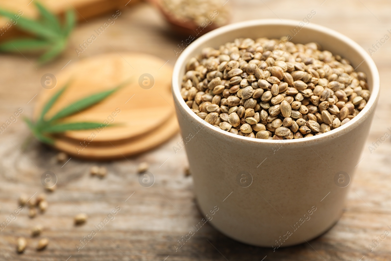 Photo of Organic hemp seeds in bowl on wooden table