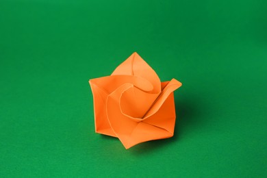Photo of Origami art. Handmade orange paper flower on green background