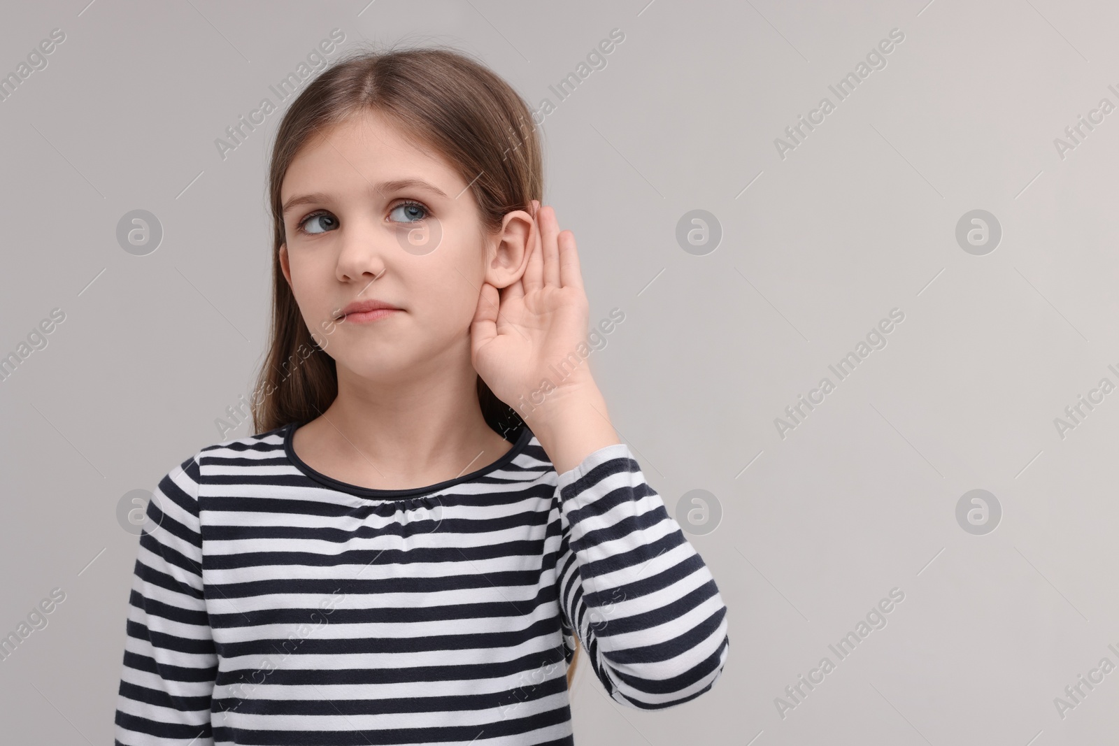 Photo of Little girl with hearing problem on grey background, space for text