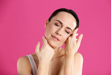 Portrait of beautiful mature woman on pink background