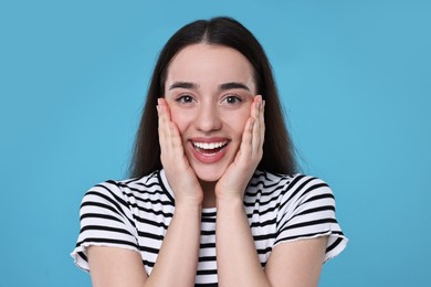 Photo of Portrait of happy surprised woman on light blue background