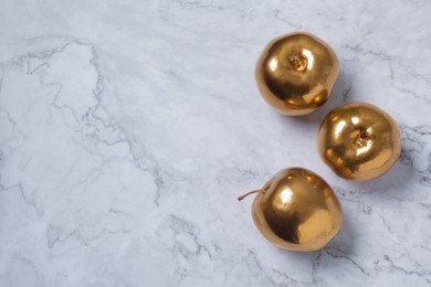 Golden apples on white marble table, flat lay. Space for text