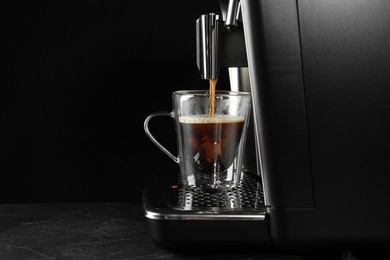 Making coffee with modern espresso machine on grey table against black background. Space for text