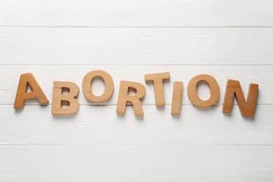 Photo of Word Abortion made of letters on white wooden background, flat lay