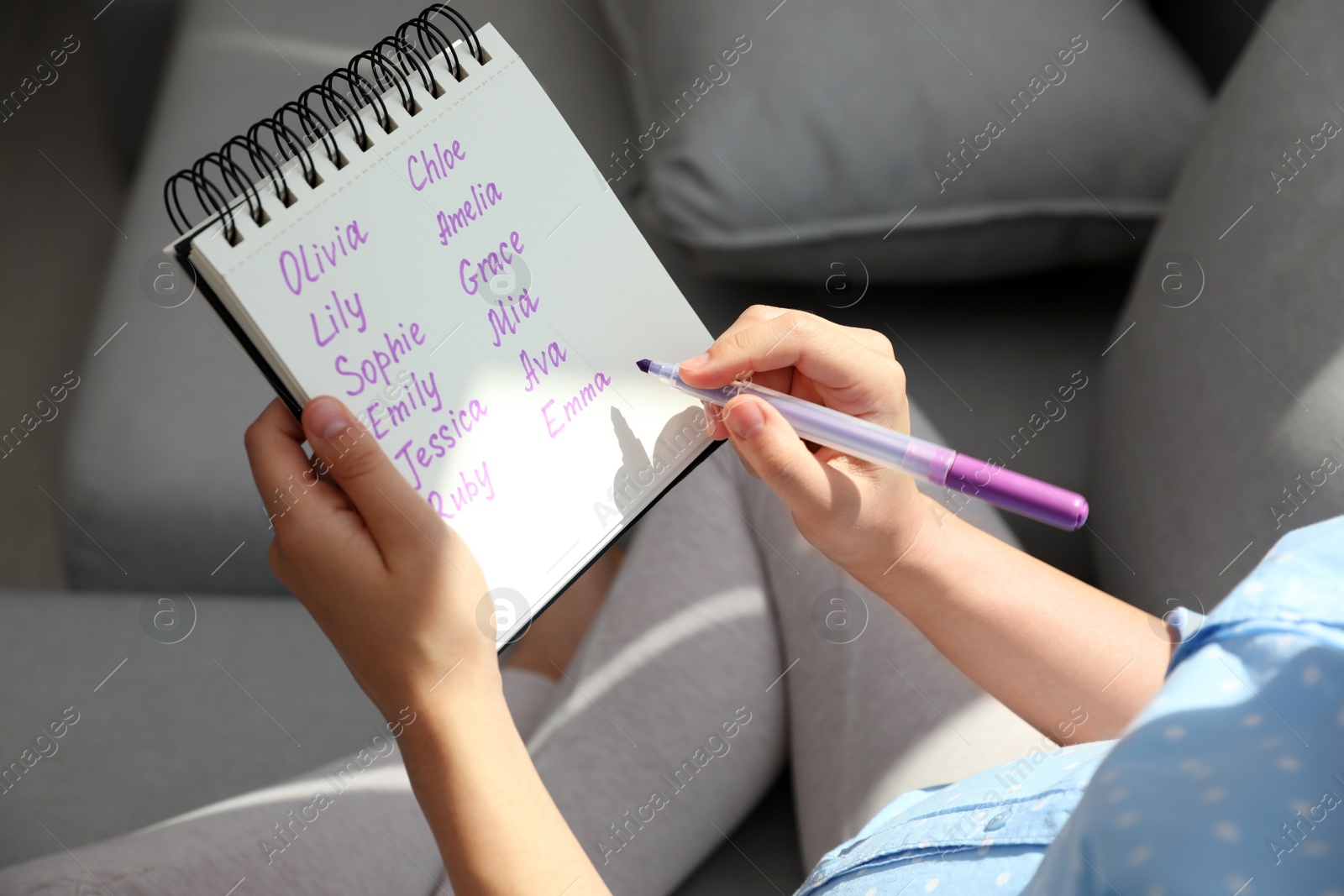 Photo of Pregnant woman with baby names list sitting on sofa, closeup