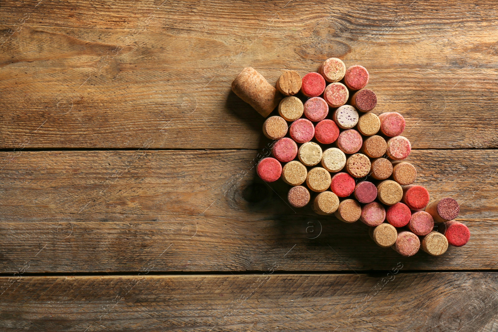 Photo of Grape made of wine bottle corks on wooden table, top view. Space for text