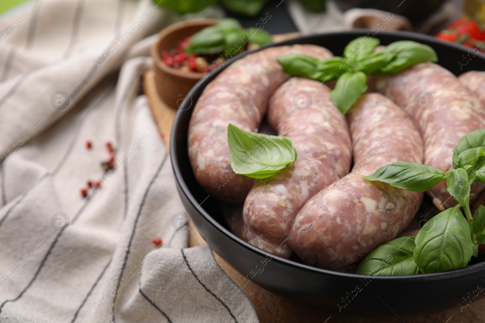 Photo of Raw homemade sausages and basil leaves on table, closeup. Space for text