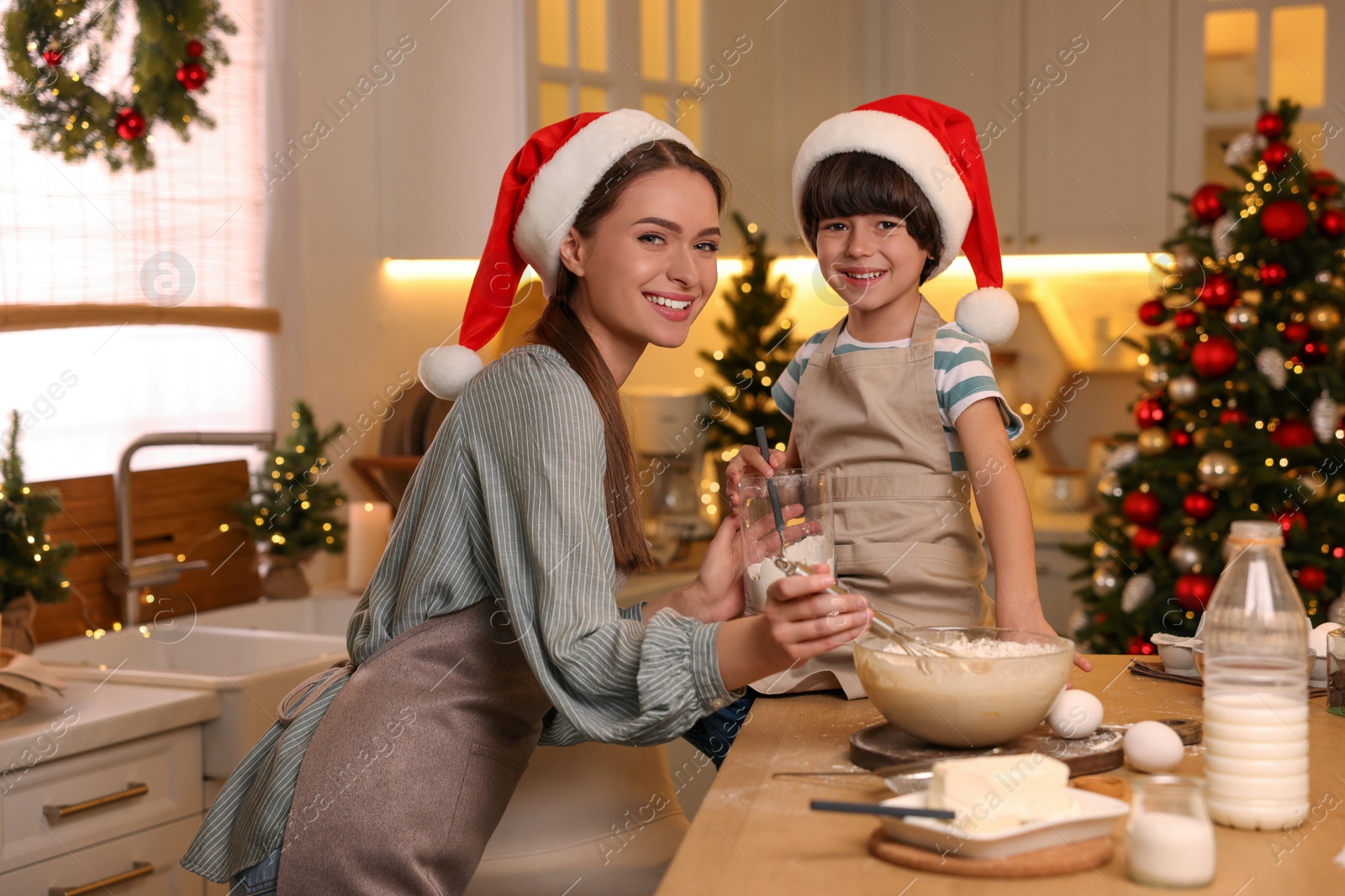 Photo of Mother with her cute little son making dough for Christmas cookies in kitchen