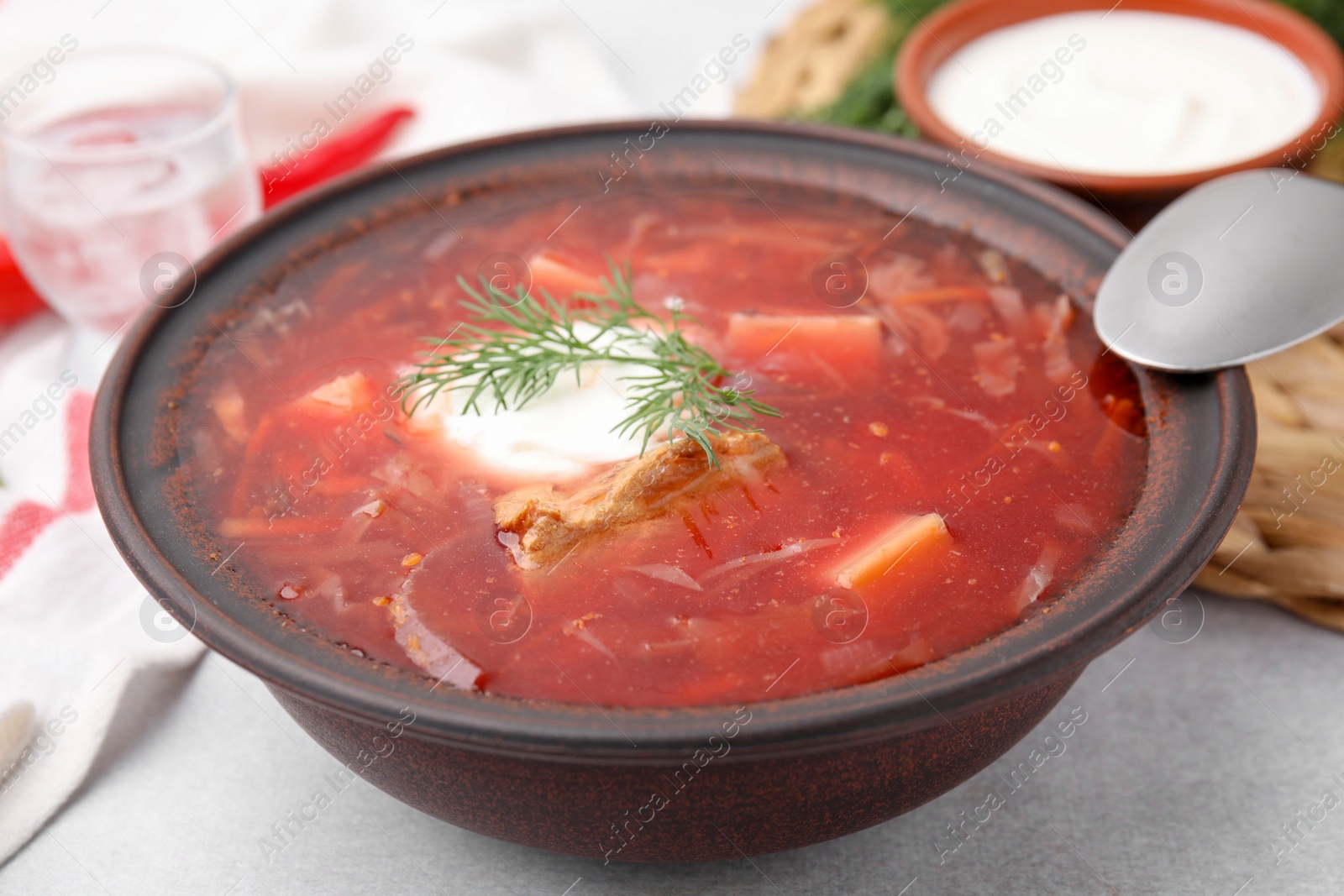 Photo of Tasty borscht with sour cream in bowl on grey table, closeup