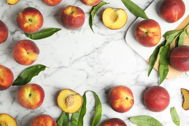 Photo of Flat lay composition with ripe peaches, leaves and board on marble table, space for text