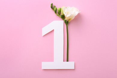 Paper number 1 and beautiful freesia flower on pink background, top view