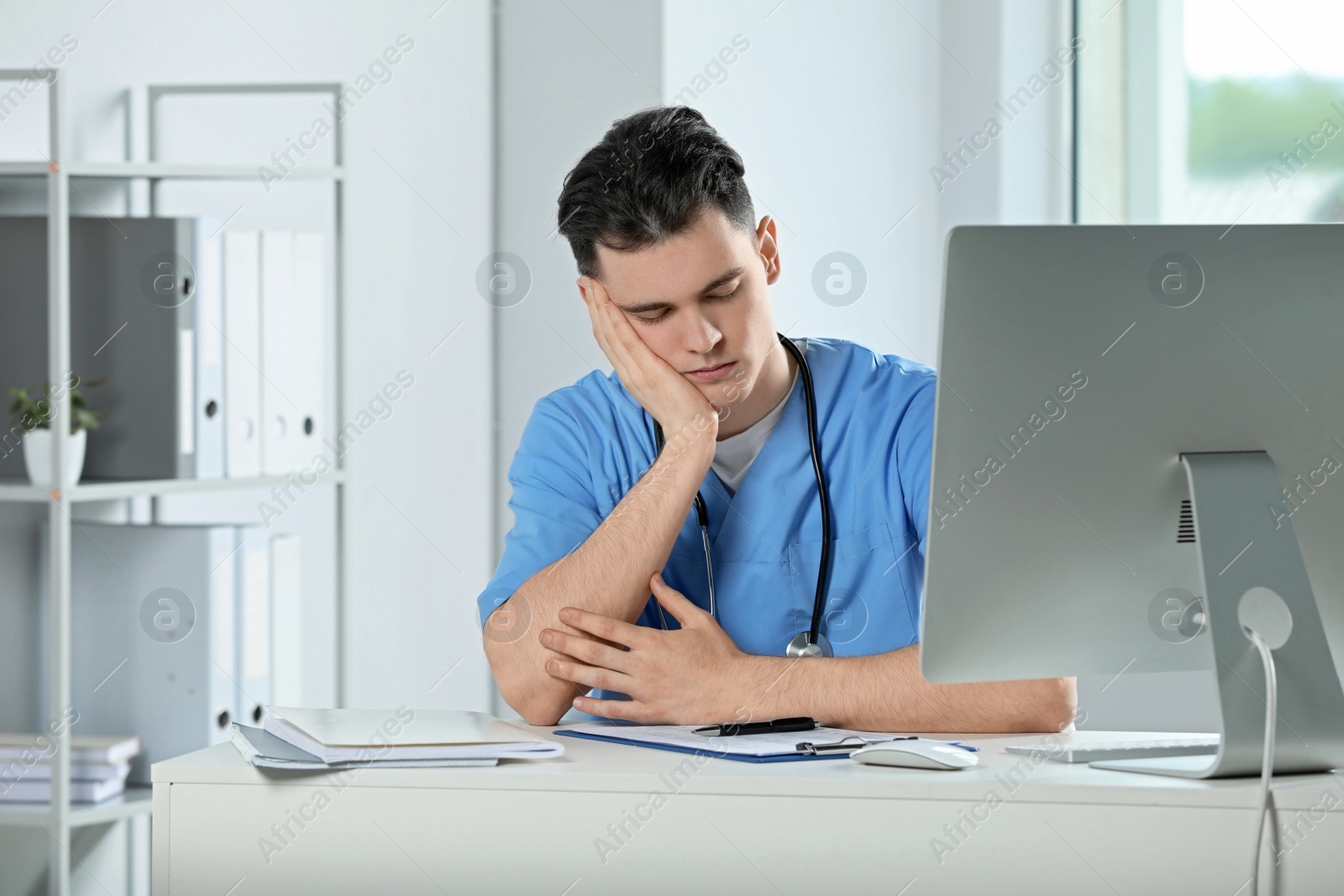 Photo of Exhausted doctor sleeping at workplace in hospital