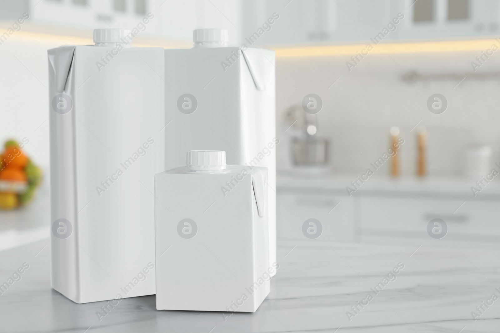 Photo of Carton boxes of milk on table in kitchen, space for text