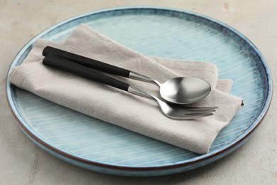 Photo of Stylish setting with cutlery, napkin and plate on light grey table, closeup