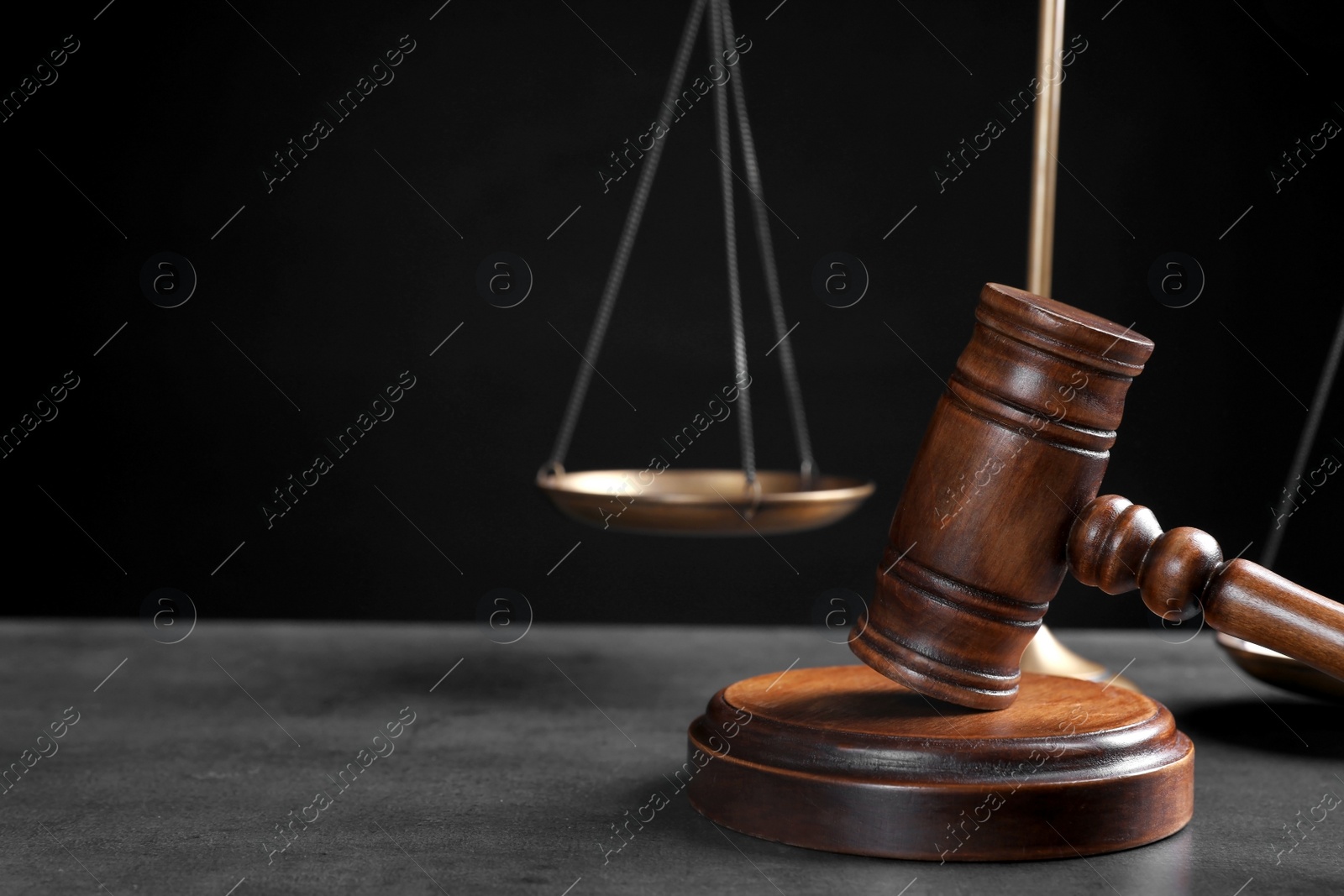 Photo of Judge's gavel and scales on grey table against black background, space for text. Criminal law concept