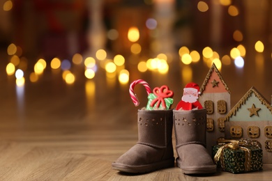 Photo of Boots filled with sweets and gift on floor in room, space for text. Saint Nicholas Day