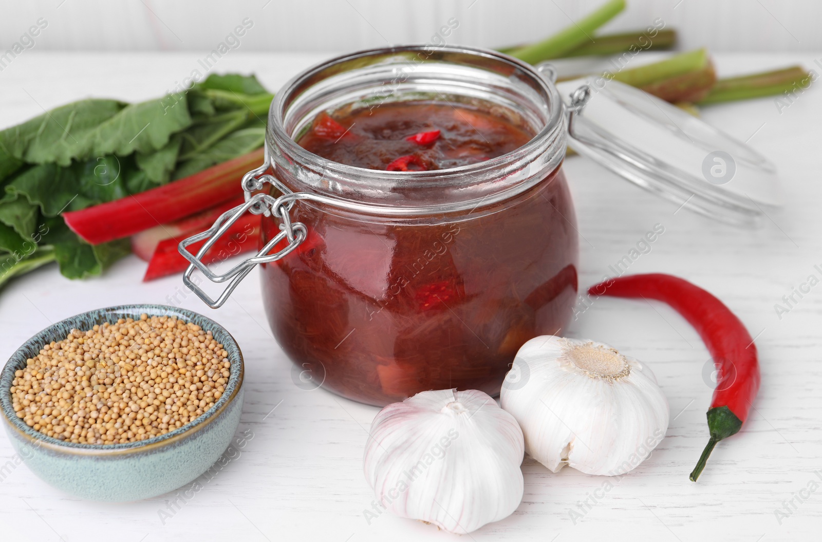 Photo of Tasty rhubarb sauce and ingredients on white wooden table