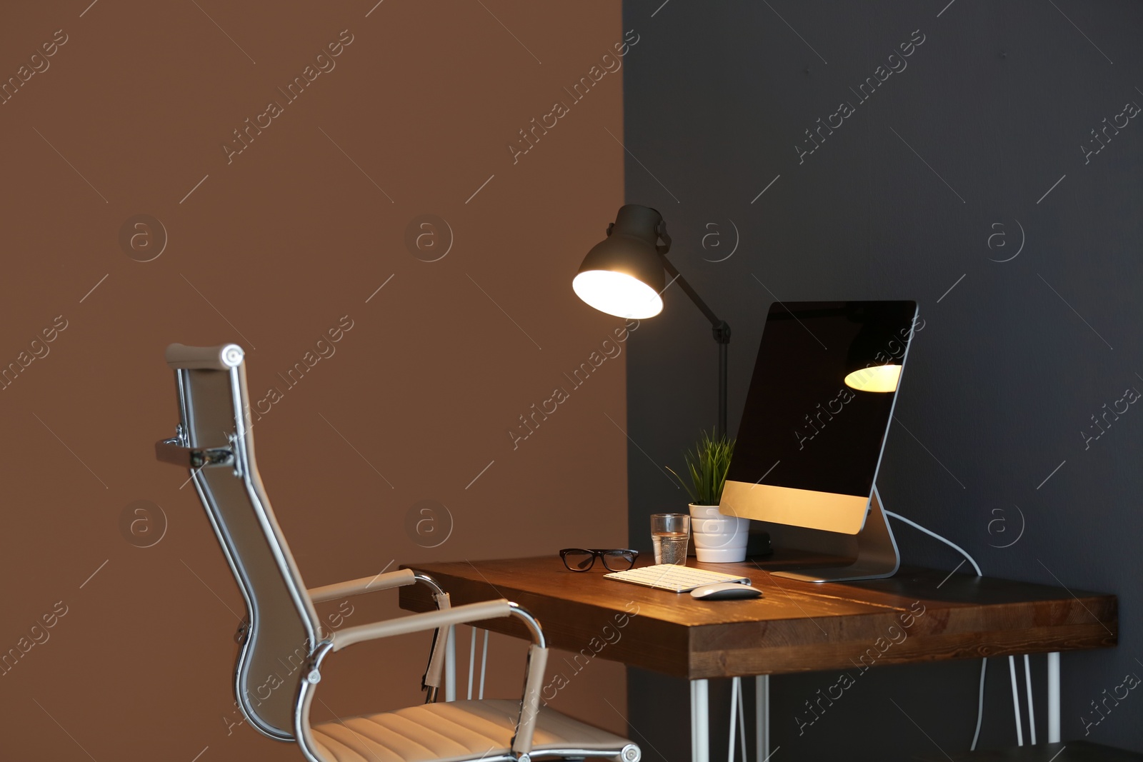 Photo of Comfortable workplace with modern lamp and computer