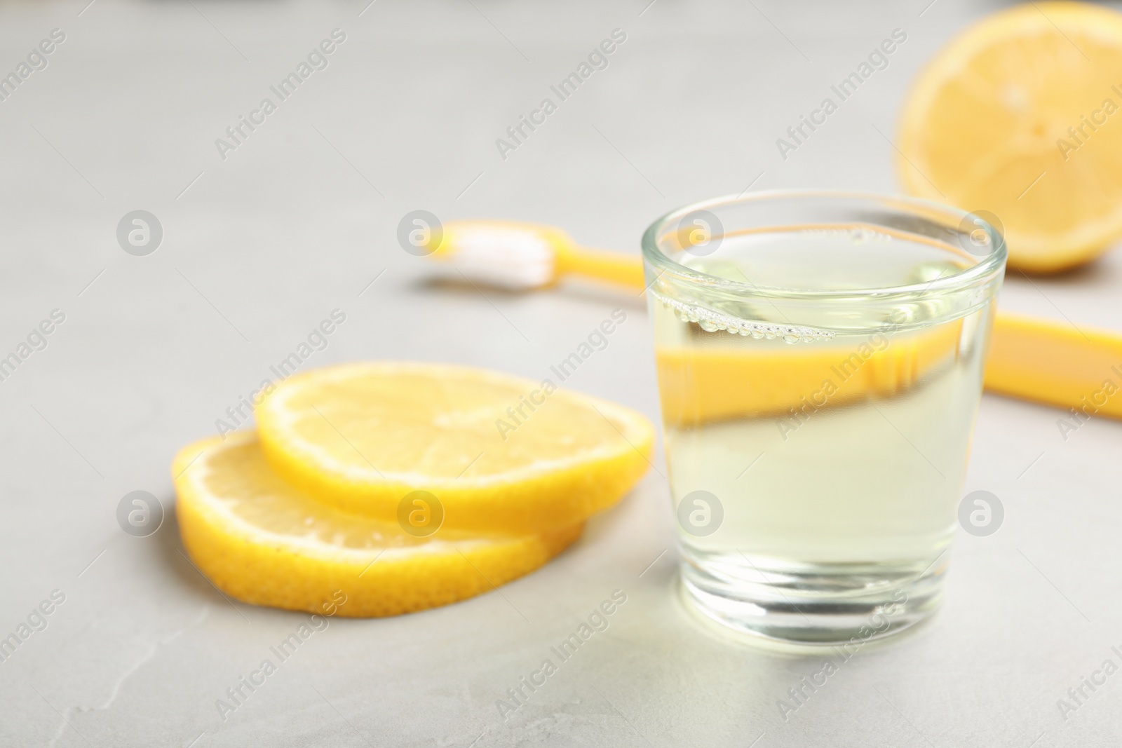 Photo of Glass with mouthwash and lemon on light background. Teeth care