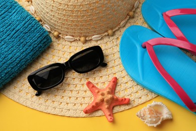 Different beach accessories on yellow background, above view