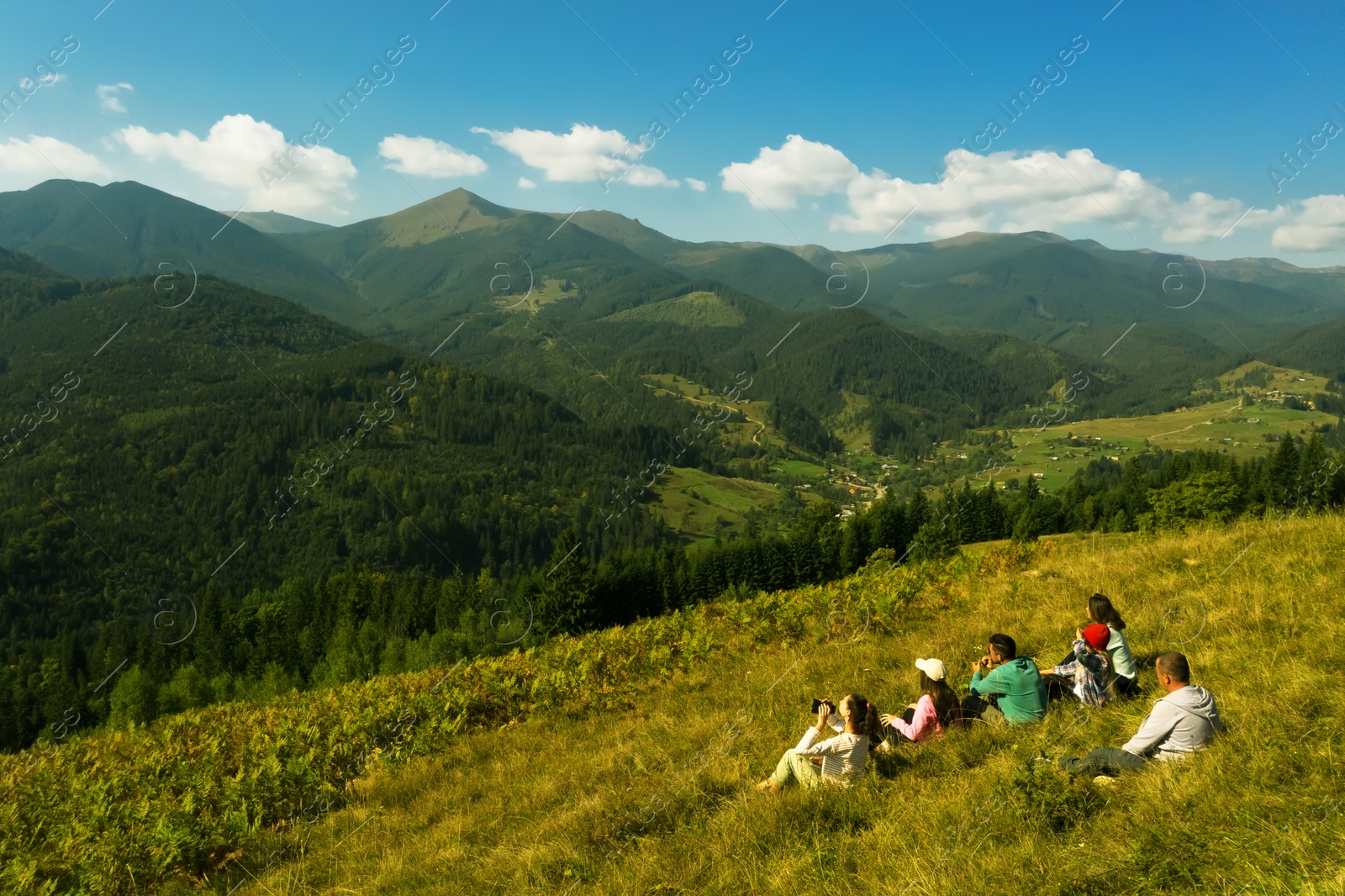 Image of Group of tourists sitting on hill in mountains