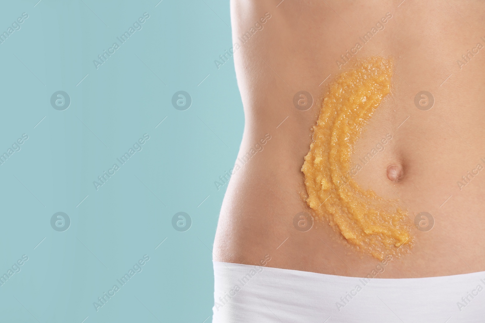 Photo of Young woman with natural scrub on her belly against color background, closeup