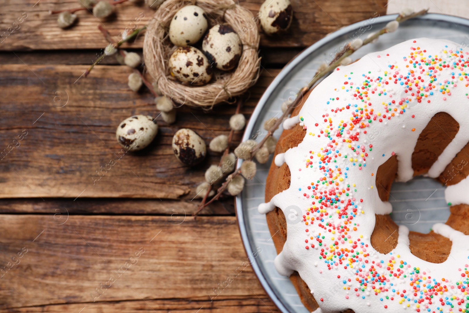 Photo of Glazed Easter cake with sprinkles and quail eggs on wooden table, flat lay. Space for text