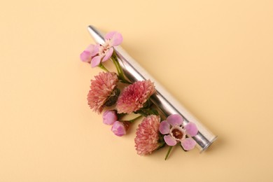 One metal bullet and beautiful flowers on yellow background, closeup