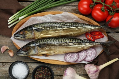 Delicious smoked mackerels and spices on wooden table, flat lay