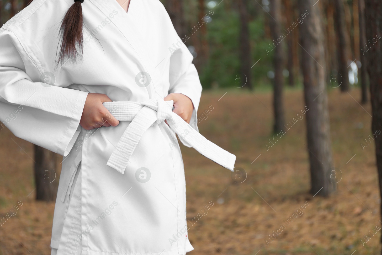 Photo of Cute little girl in kimono in forest, closeup. Karate practicing