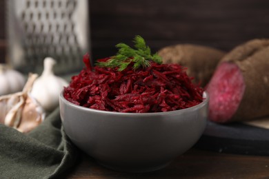 Photo of Grated red beet and dill in bowl on table, closeup