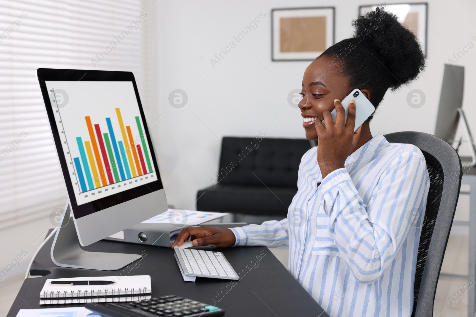 Photo of Professional accountant talking on phone and working at desk in office