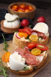 Photo of Delicious sandwiches with burrata cheese, ham, radish and tomatoes served on table, closeup