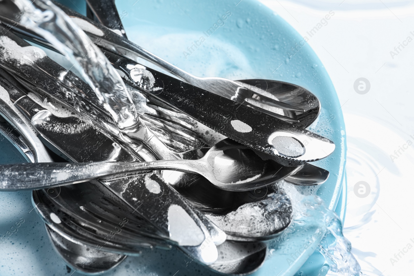 Photo of Pouring water onto silverware in foam, closeup