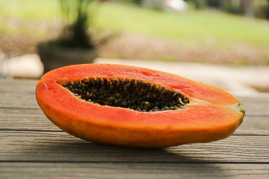 Photo of Fresh ripe papaya fruit on wooden table outdoors