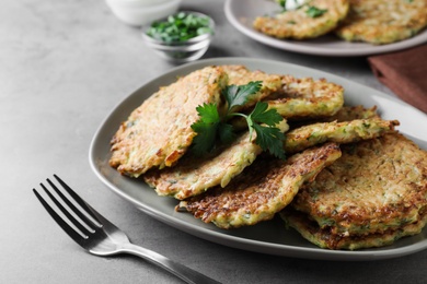Photo of Delicious zucchini fritters served on grey table, closeup