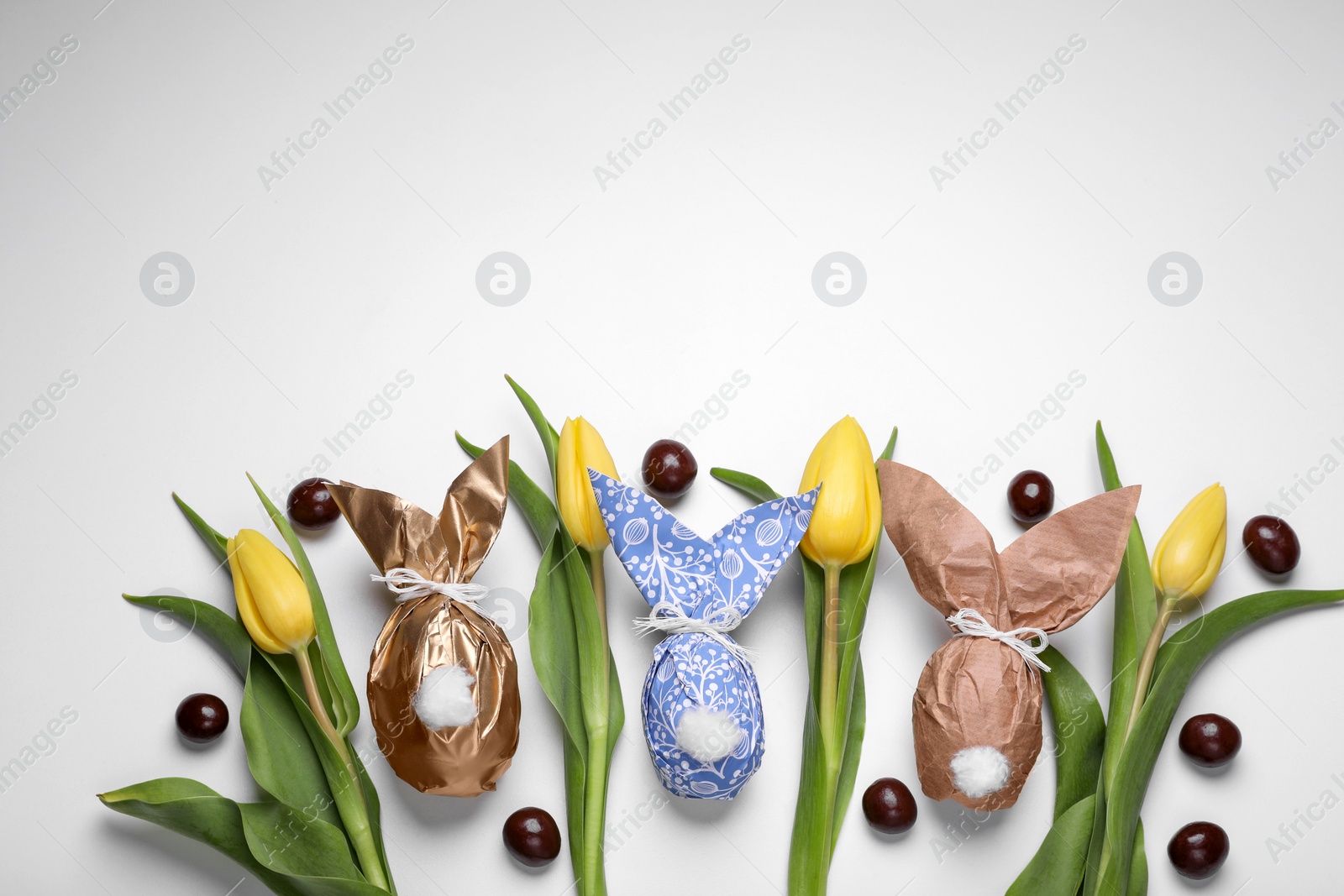 Photo of Flat lay composition with Easter bunnies made of paper and eggs on white background. Space for text