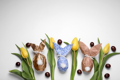 Photo of Flat lay composition with Easter bunnies made of paper and eggs on white background. Space for text
