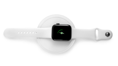 Smartwatch charging with wireless pad isolated on white, top view