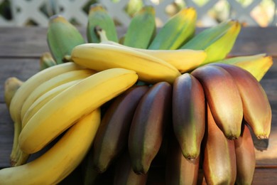 Different sorts of bananas on wooden table, closeup