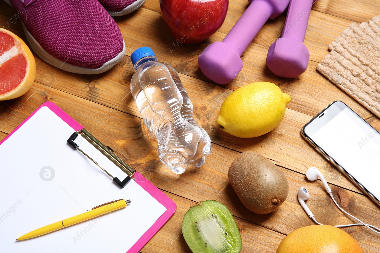 Photo of Composition with sport items, healthy food and clipboard on wooden background. Weight loss concept