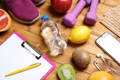 Composition with sport items, healthy food and clipboard on wooden background. Weight loss concept